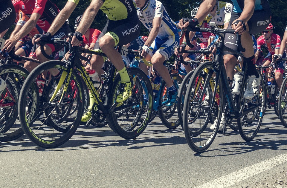 a close up of a large group of cyclists, biking along a path