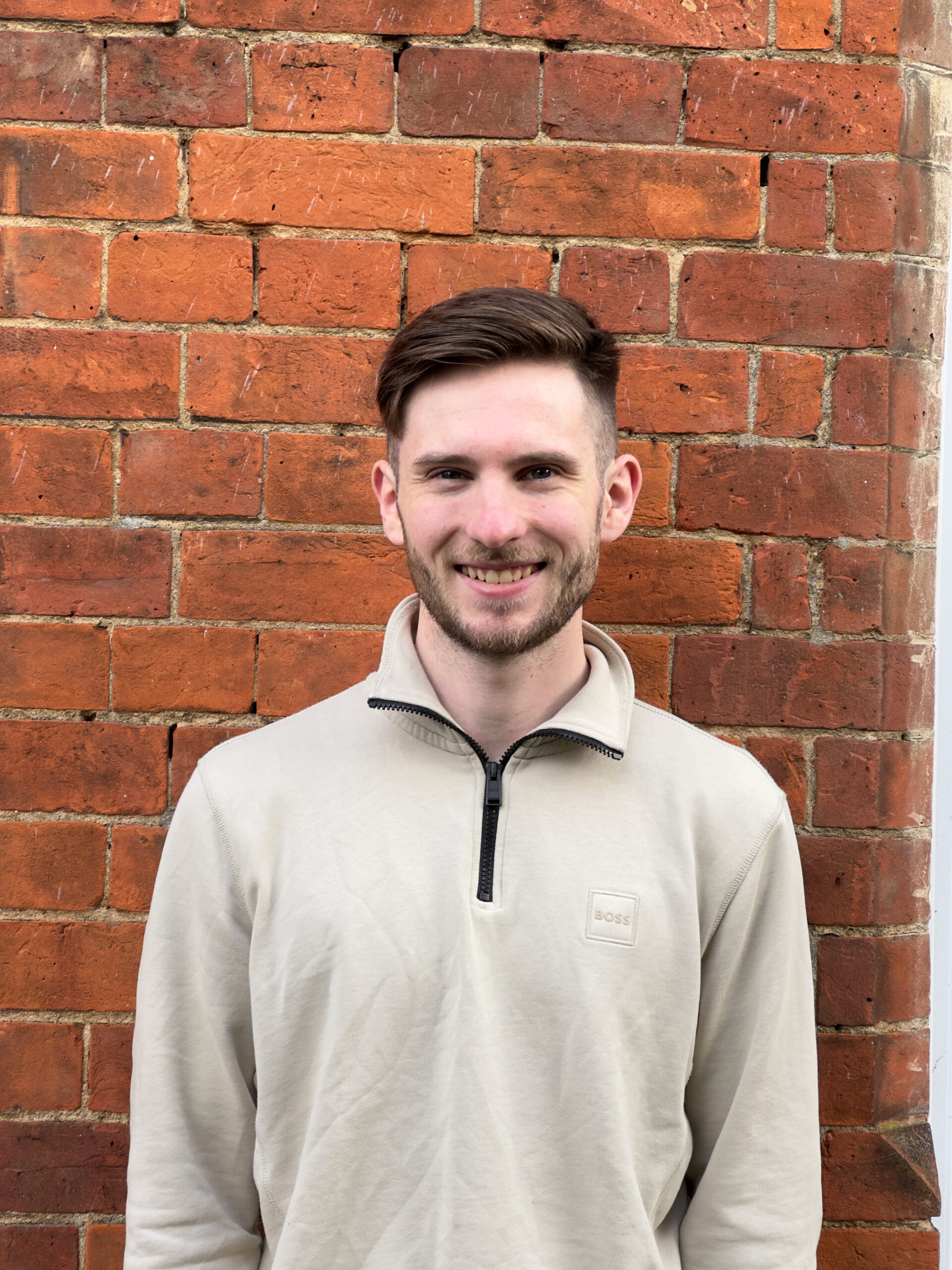 George smiling infront of a brick wall