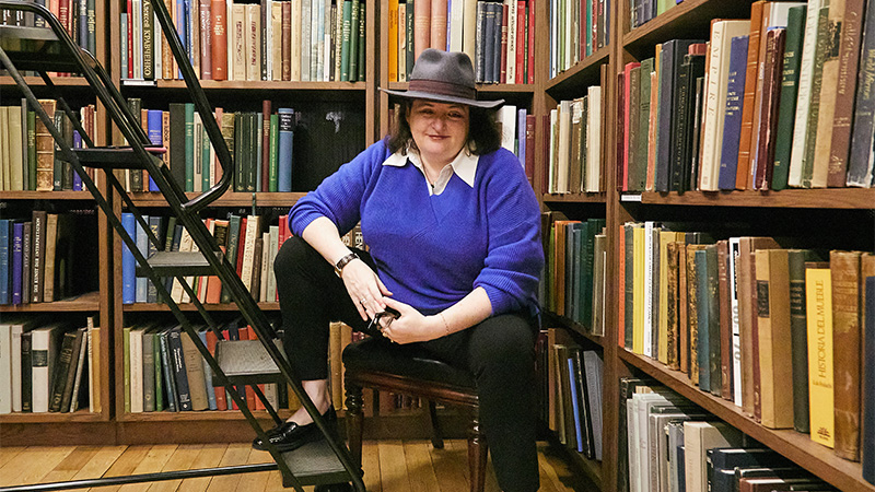 Photo of a lady sitting in front of a bookshelf